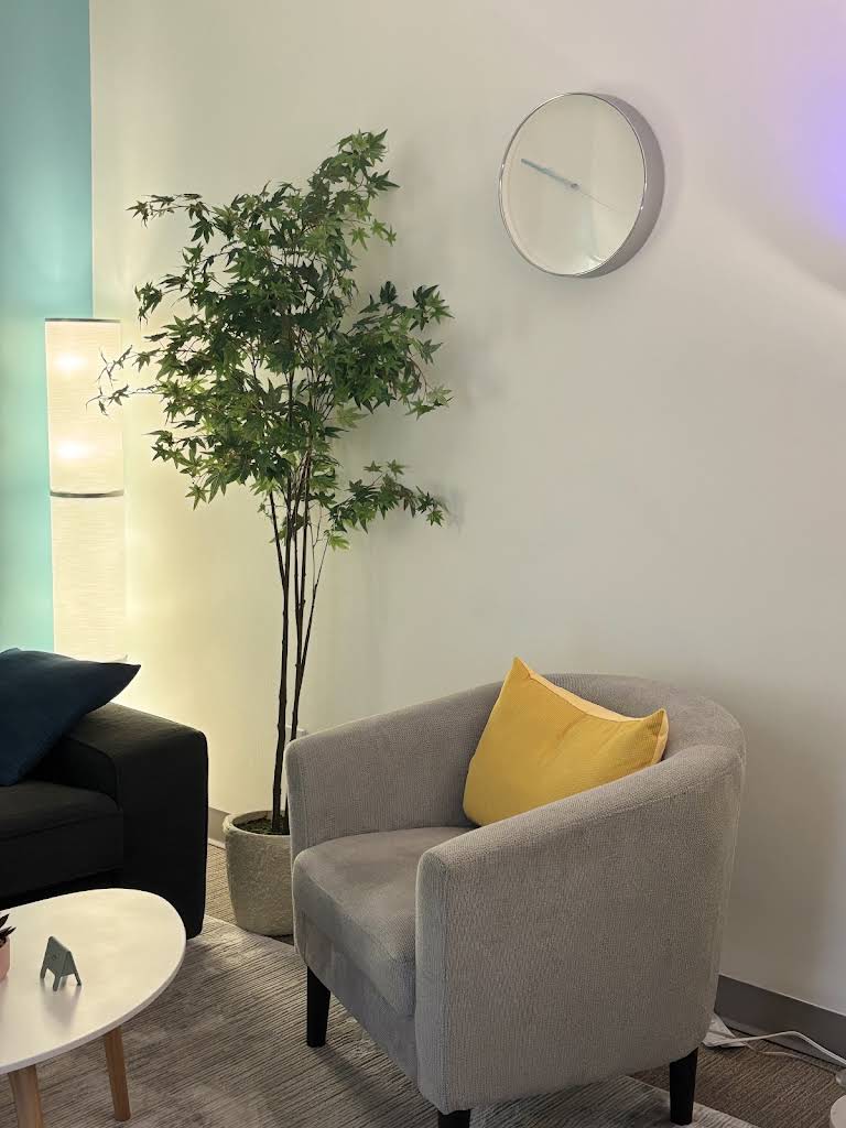 Softly glowing floor lamp beside a leafy plant and a comfortable armchair in the therapy room